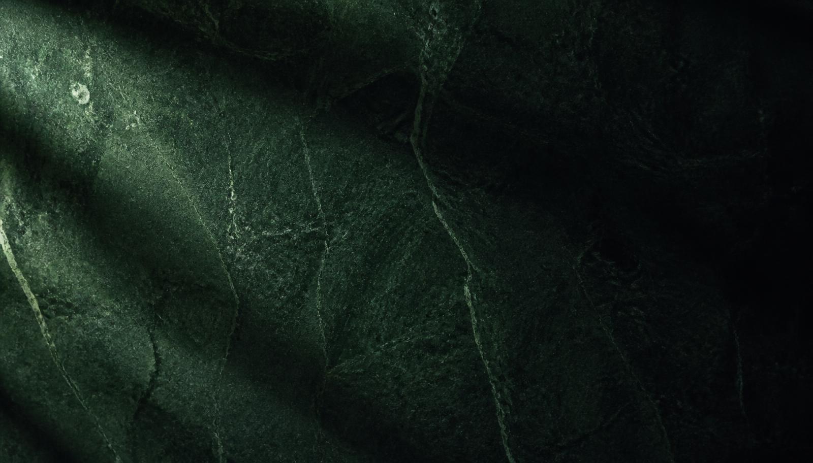 Deep green stone surface under raking light
